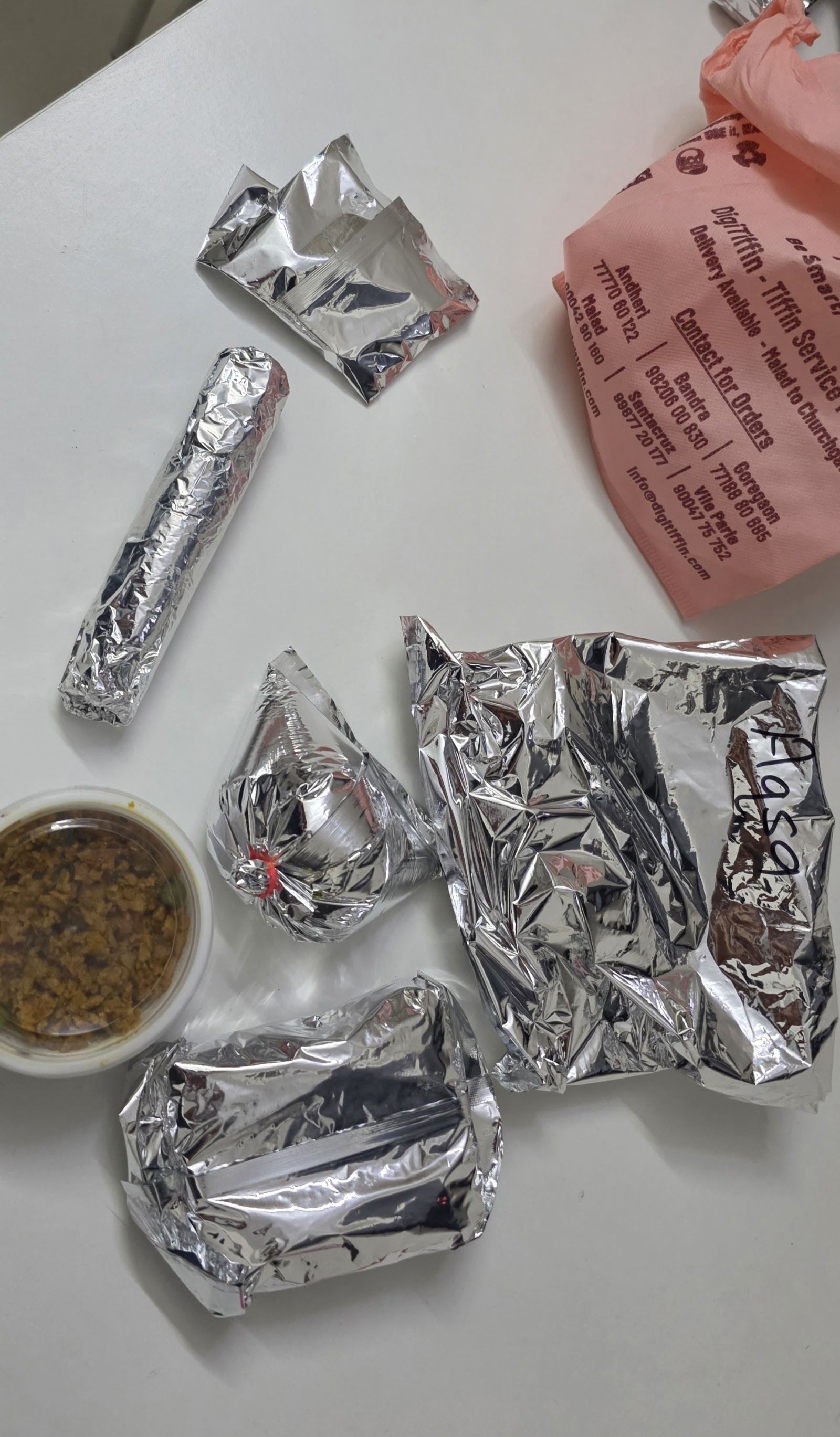 Foil-wrapped tiffin portions freshly packed for delivery